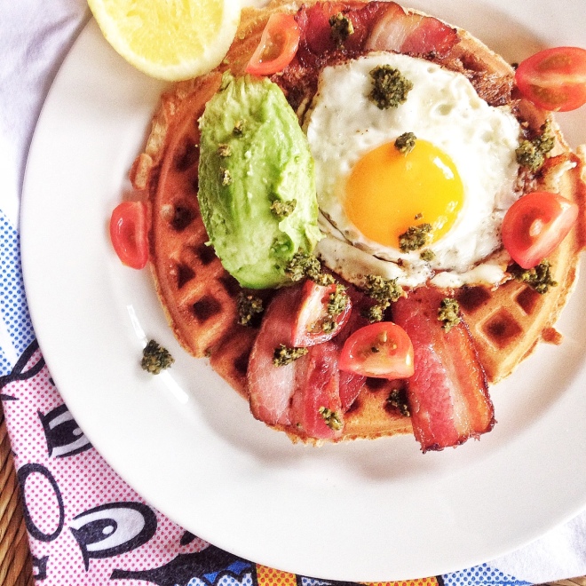 Plain waffle with egg, bacon, avocado, kale and sunflower seed pesto and tomatoes.